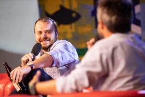 Mężczyzna z mikrofonem na scenie podczas rozmowy.