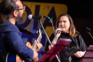 Kobieta śpiewa na scenie z gitarzystą