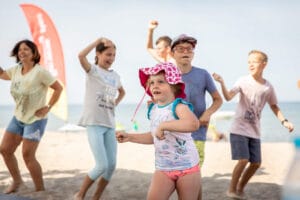 Dzieci tańczą na plaży w słoneczny dzień.