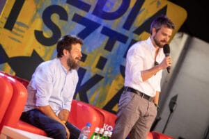 Dwóch mężczyzn na scenie podczas konferencji.