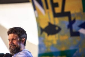 Mężczyzna na tle kolorowego obrazu ryby.