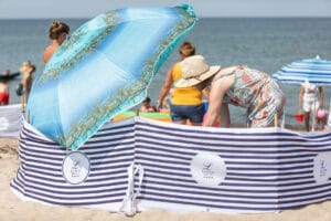 Plaża, kobieta pod parasolem, parawan w pasy.