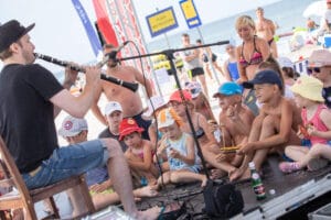 Muzyk gra dzieciom na plaży klarnecie.