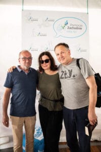 Trzy osoby pozują na tle plakatu Pomorze Zachodnie.