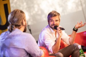 Mężczyzna prowadzi rozmowę na scenie z mikrofonem.