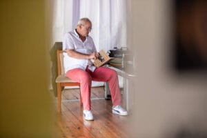 Mężczyzna czyta książkę na krześle w pokoju.