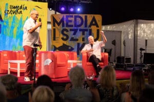 Dwóch mężczyzn na scenie podczas wydarzenia medialnego.