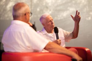 Dwaj mężczyźni rozmawiają na scenie, jeden trzyma mikrofon