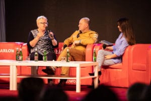 Trzy osoby na scenie, dyskusja panelowa, mikrofony.