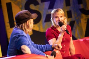 Dwie osoby z mikrofonami na scenie.