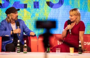 Dwoje ludzi rozmawia na scenie z mikrofonami.