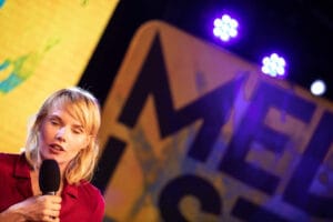 Osoba z mikrofonem na scenie, kolorowe oświetlenie