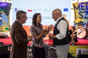 Ludzie rozmawiający na scenie podczas wydarzenia.